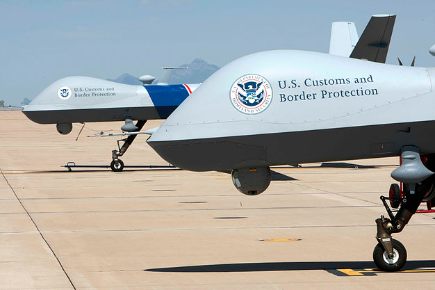Two U.S. Customs and Border Protection unmanned aircraft on the tarmac, marked with the CBP and DHS seals.