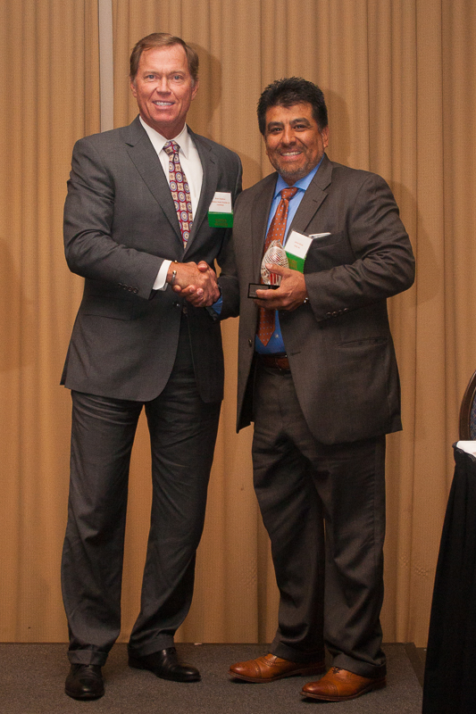 Dr. Johnny Garcia shaking hands and receiving the Workforce Innovation Award trophy at the Opportunity Inc. ceremony.