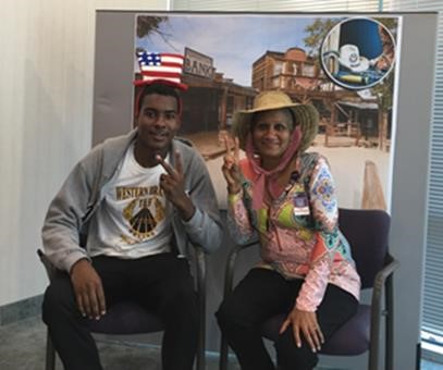 Two attendees in themed hats posing at the old west photo booth during the cookout.