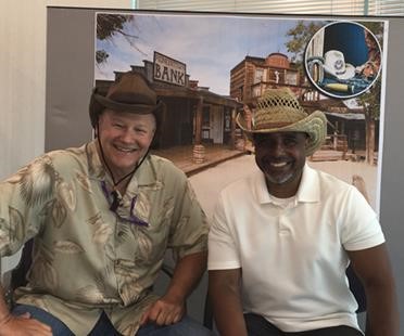 Two attendees wearing cowboy hats posing at the old west photo booth during the cookout.