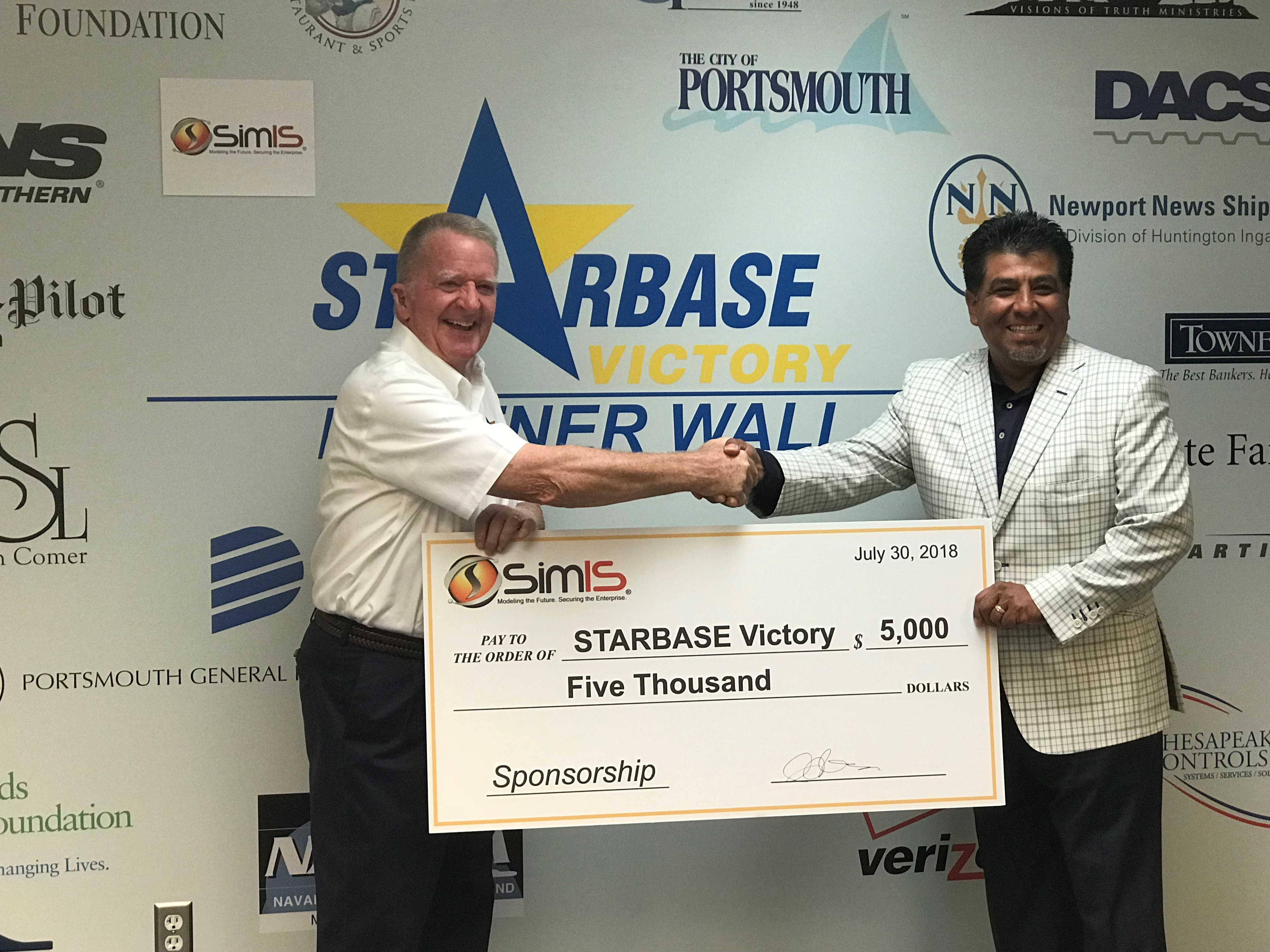 Dr. Johnny Garcia presents a $5,000 SimIS sponsorship check to a STARBASE Victory representative, dated July 30, 2018.