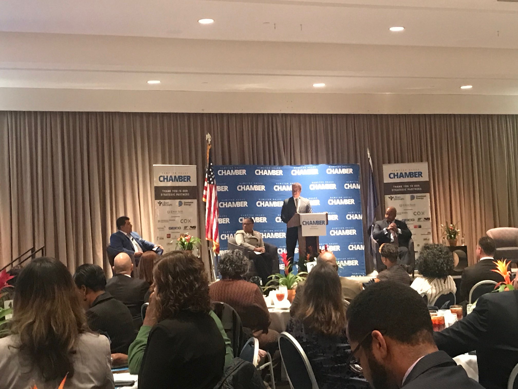 Panelists on stage at the Hampton Roads Chamber Diversity in Business Forum, with a moderator speaking at the podium.