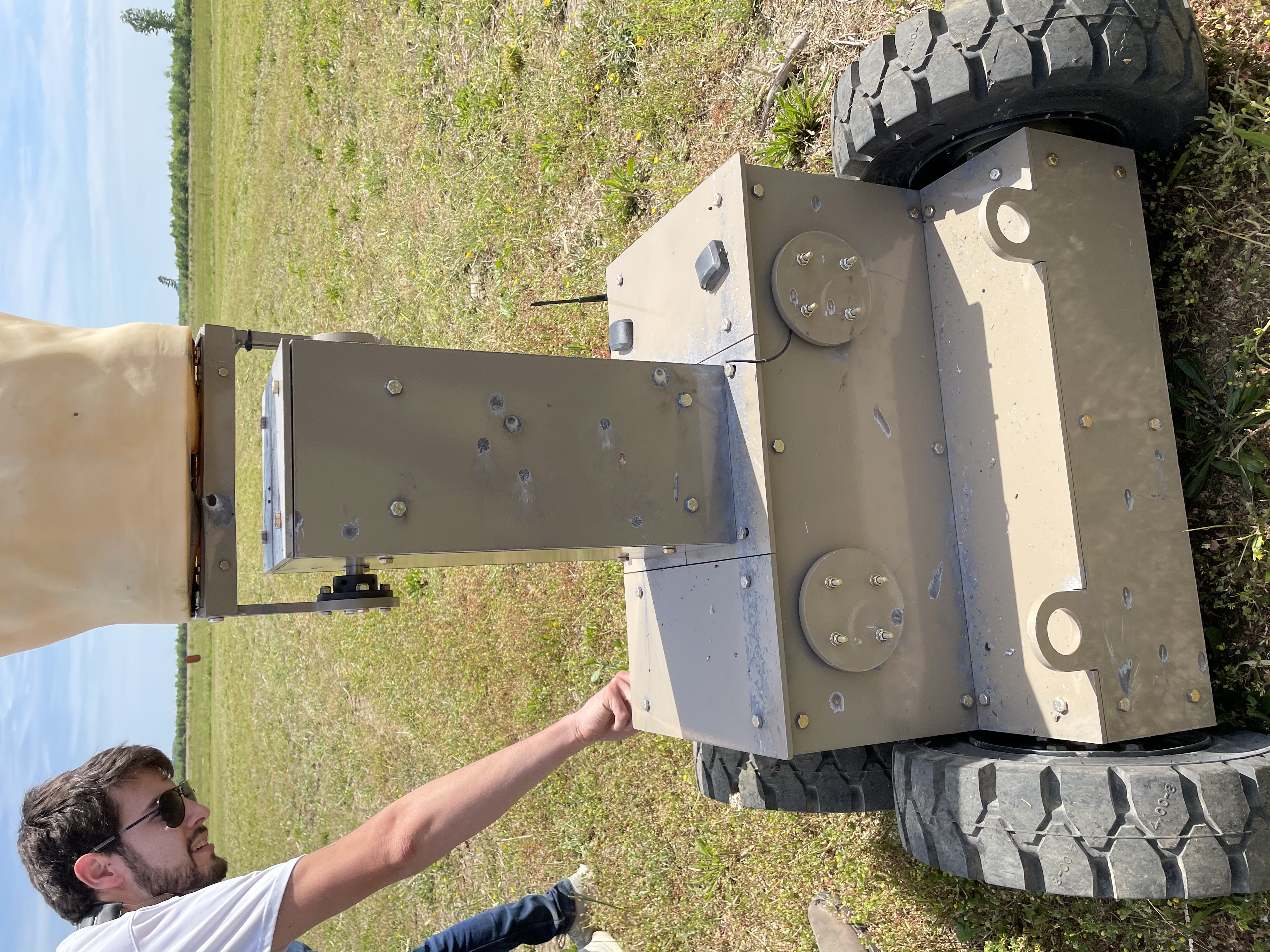 A SimIS team member inspects an HTT target's armored torso section, showing impact marks from the training exercise.