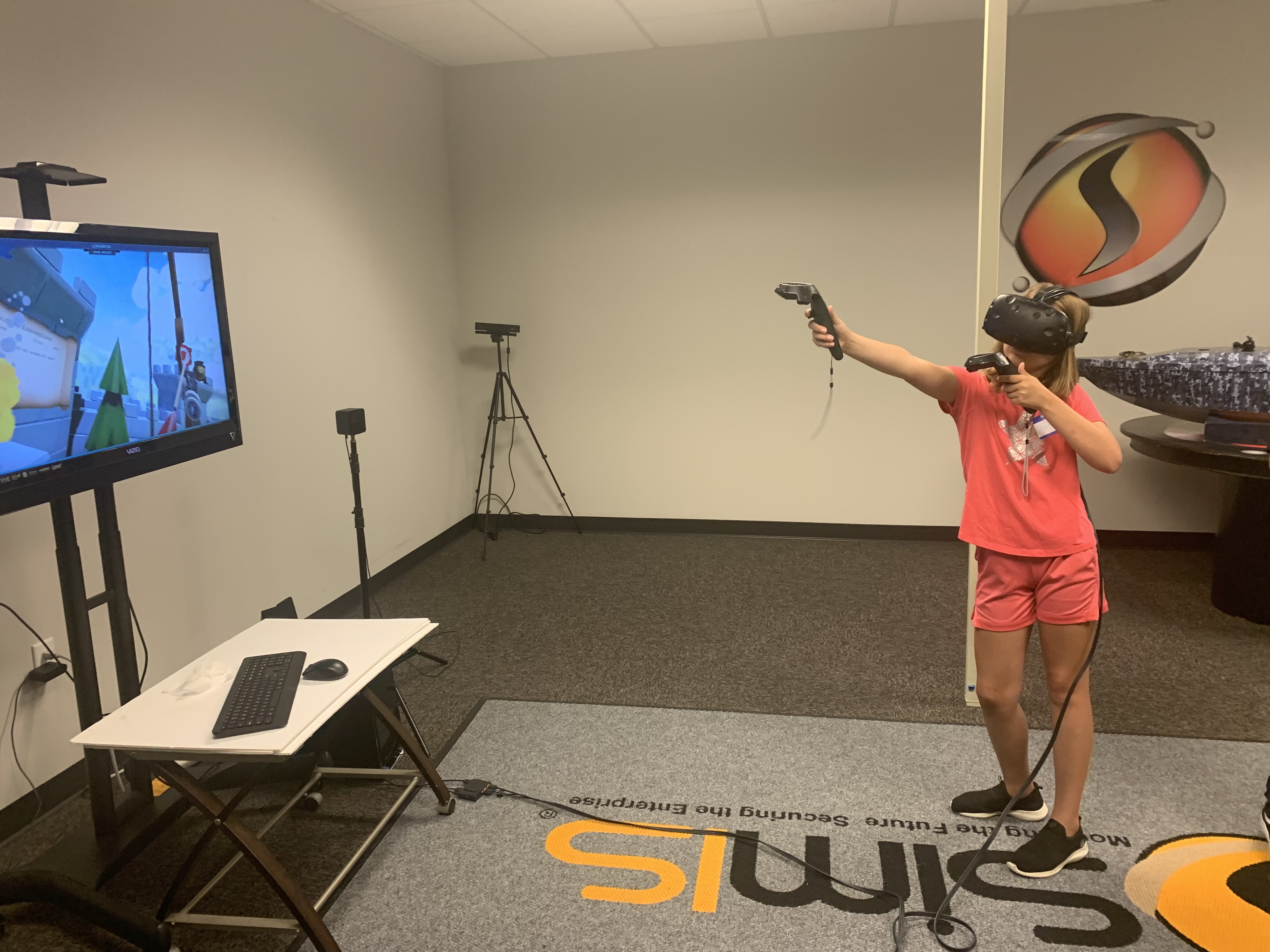 A student wearing a VR headset and holding motion controllers, playing a virtual reality game in the SimIS training room.
